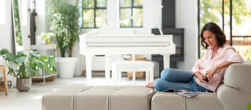 YAMAHA: Frau auf dem Sofa vor dem weißen Flügel